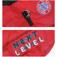 Cargar la imagen en la vista de la galería, Close-up of red dog jacket fabric showing "Next Level" text and zipper with leash attachment ring