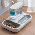 Charger l'image dans la visionneuse de la galerie, White and gray automatic pet feeder with dual compartments filled with dry food and water reservoir on wooden floor