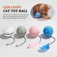 Load image into Gallery viewer, Four LED light cat toy balls in white, grey, pink, and blue colors with feathers and bells attached, inset circle showing cat playing
