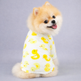 Charger l'image dans la visionneuse de la galerie, Small fluffy dog in white pajamas decorated with yellow duck patterns, sitting and smiling with tongue out