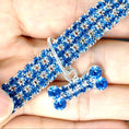 Charger l'image dans la visionneuse de la galerie, Close-up of blue rhinestone dog collar with matching crystal bone charm held in hand