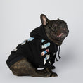 Load image into Gallery viewer, Front-facing French bulldog wearing black artistic printed hoodie sitting and looking up with visible sleeve and chest print