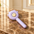 Load image into Gallery viewer, Purple pet grooming comb with cream release button on brown marble