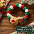 Load image into Gallery viewer, Plush Christmas collar with red and green felt balls featuring a smiling reindeer head and wrapped gift ornament on wooden surface