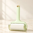 Load image into Gallery viewer, Pale-green lint roller with clear cover and hanging loop on ivory marble