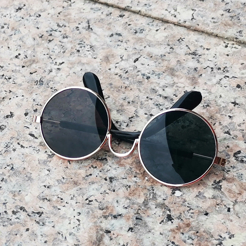 Metallic gold-framed round sunglasses with black lenses on stone surface