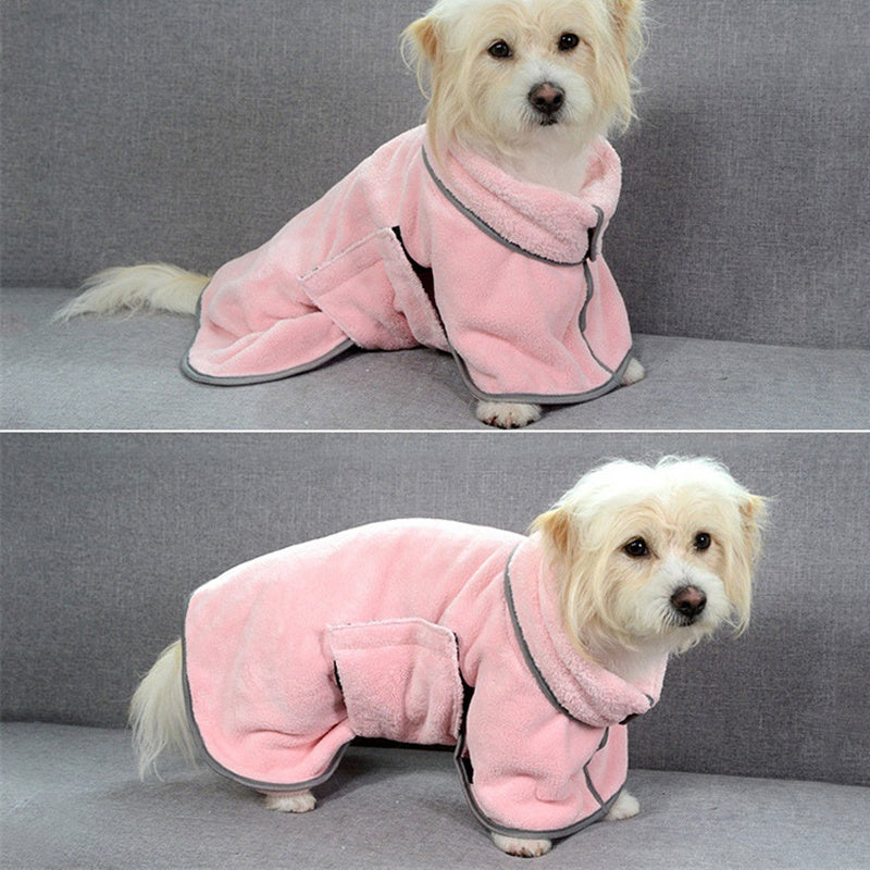 Small white dog wearing a pink microfiber drying robe sitting on gray couch, front view