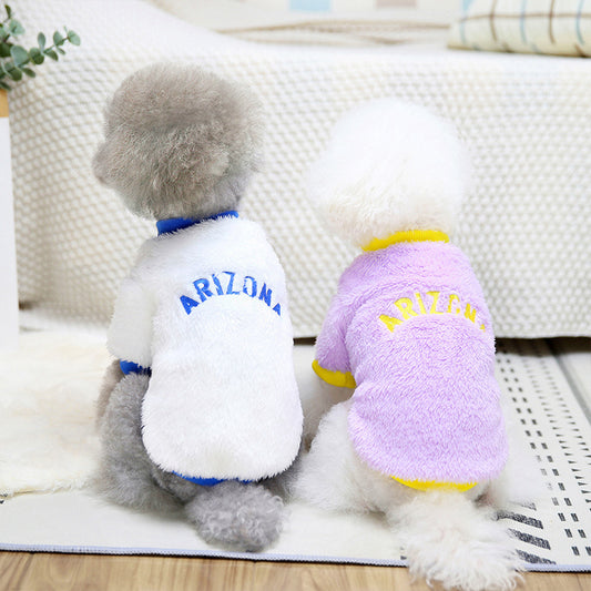 Two small dogs wearing Arizona fleece dog jumpers, one white with blue trim, the other lavender with yellow trim, sitting with backs facing camera