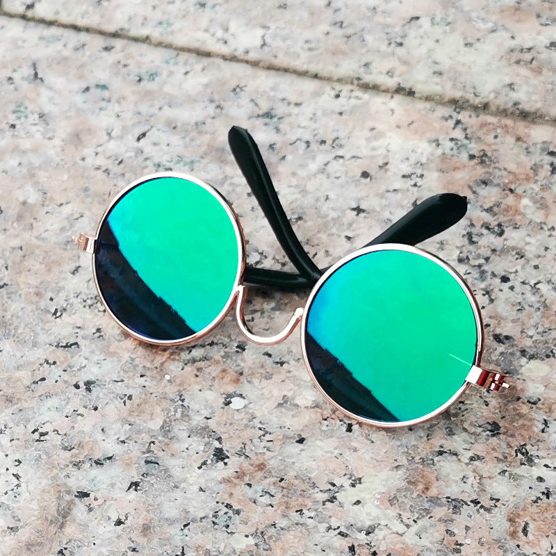 Metallic gold-framed round sunglasses with rainbow mirrored lenses on stone surface