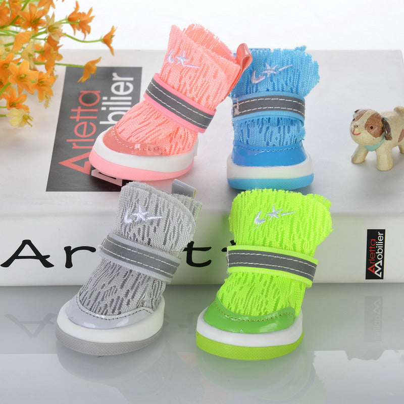 Multiple dog booties in pink, blue, gray, and neon green knit colors arranged on white surface