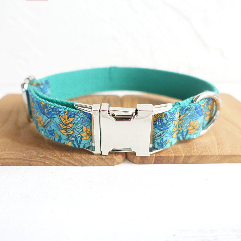 Close-up of teal floral dog collar with metal buckle and D-ring on wooden background