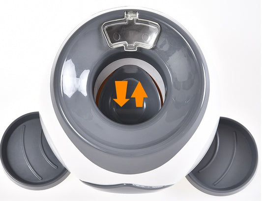 Top view of the gray and white feeder showing the treat compartment with arrows indicating motion