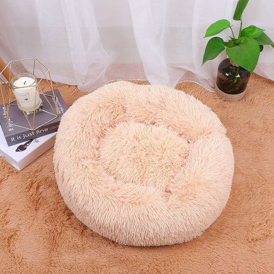 Light peach color plush round pet bed set on matching carpet near candle and plant