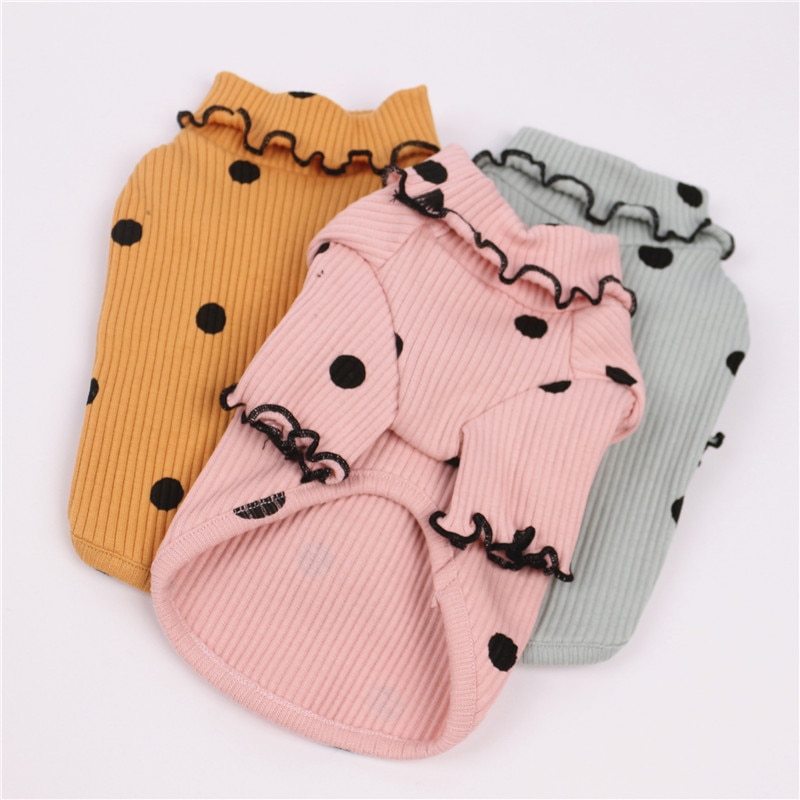 Three ribbed cotton dog shirts laid flat in yellow, pink, and mint green with black polka dots and ruffled edges