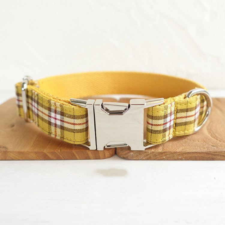 Front view of collar's metal buckle and D-ring on yellow plaid fabric