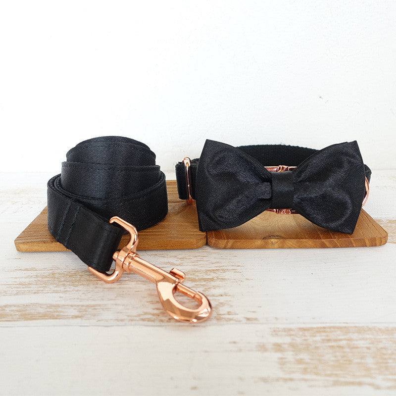 Top view of black satin pet leash and bow tie collar set on wooden board
