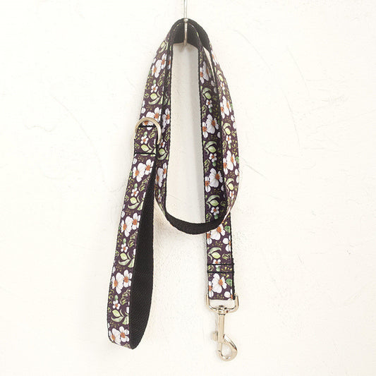 Matching floral dog leash hanging against a textured white wall