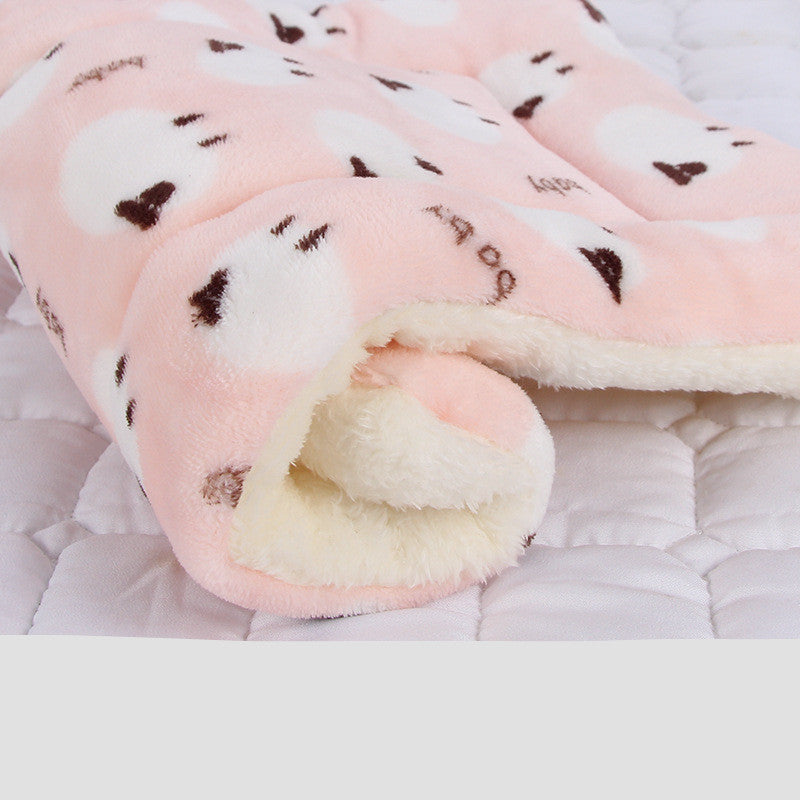 Rolled pet blanket in pale pink with white cartoon cat faces and fleece lining