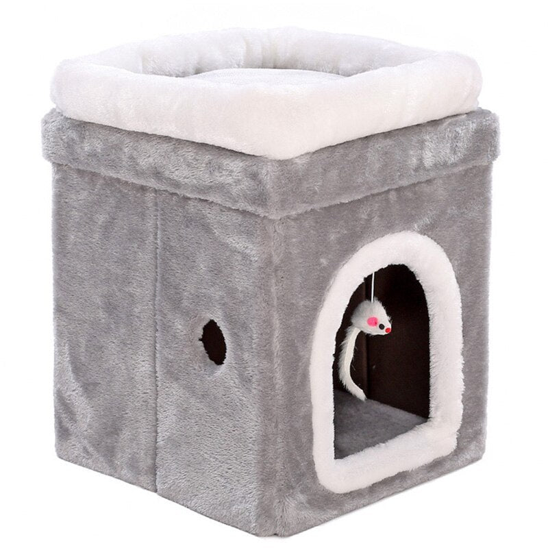 Close-up of gray plush cat cave with white trim showing cubical shape, arched entrance with hanging mouse toy inside
