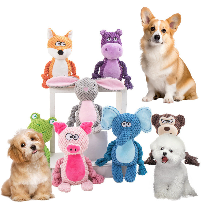 Group of colorful plush animal rope dog toys with three dogs sitting nearby