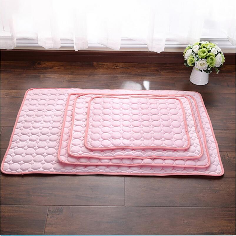 Stack of three pink pet cooling mats of different sizes displayed on wooden floor