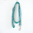 Load image into Gallery viewer, Full view of teal floral patterned dog leash hanging on white textured wall
