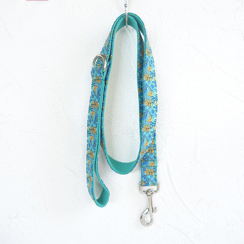 Full view of teal floral patterned dog leash hanging on white textured wall