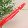 Load image into Gallery viewer, Side view of red transparent PVC dog bone toy showing spiked texture on one edge
