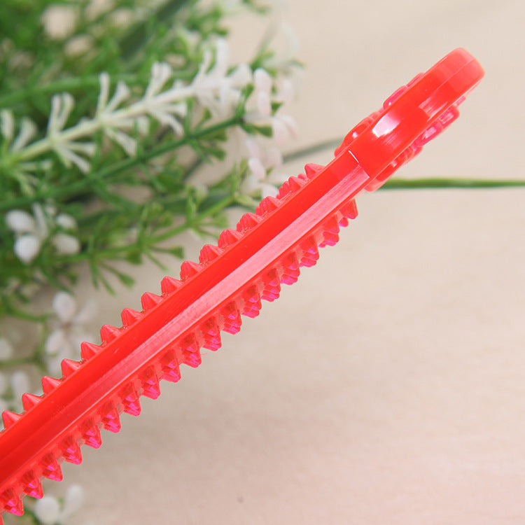 Side view of red transparent PVC dog bone toy showing spiked texture on one edge