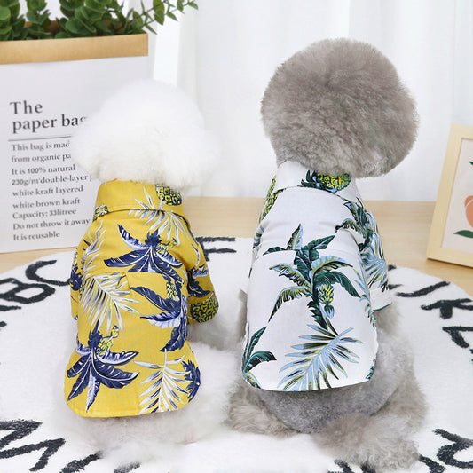 Back view of two dogs wearing Hawaiian short-sleeve shirts with tropical leaf and pineapple prints