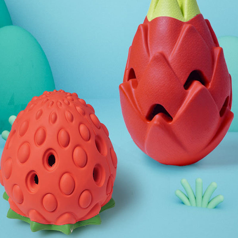 Orange strawberry-shaped and red exotic fruit-shaped rubber dog toys displayed on blue background