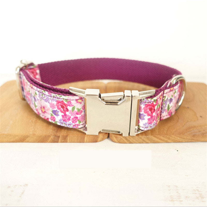 Close-up of pink floral dog collar with metal buckle on wooden surface