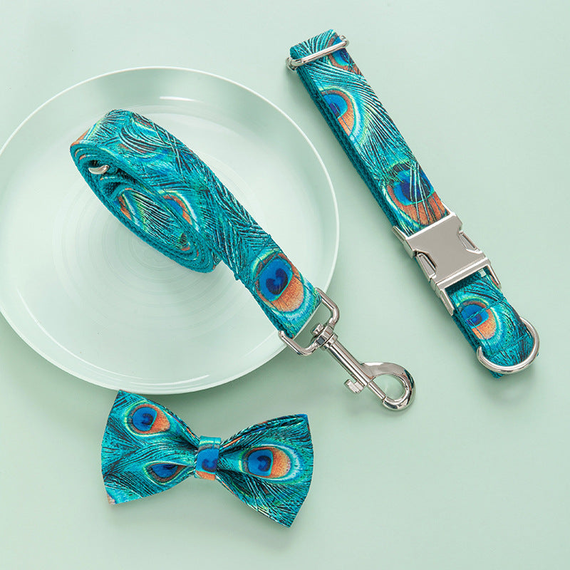 Rolled up peacock print leash alongside adjustable collar and bow tie on pale green background
