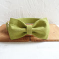 Load image into Gallery viewer, Green polyester dog collar with attached bow tie accessory on wooden panel
