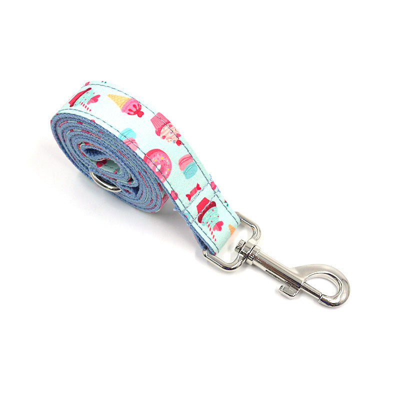 Rolled-up dog leash featuring blue fabric with fun cupcake, ice cream, and candy design