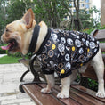 Load image into Gallery viewer, Side view of French Bulldog in black patterned jumper with sun and text motifs standing on wooden bench outdoors
