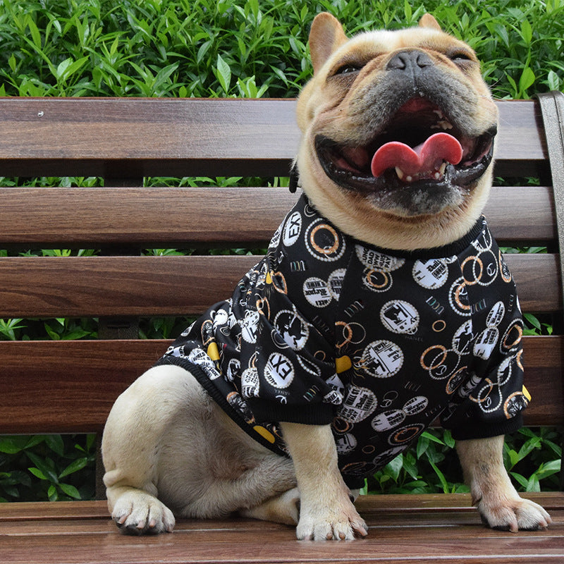 Happy French Bulldog wearing black jumper with circular graphic prints sitting on wooden bench