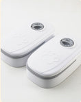 Charger l'image dans la visionneuse de la galerie, Two white automatic pet feeders with closed lids and paw-print embossed covers, viewed from above
