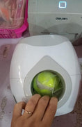 Load image into Gallery viewer, Hand placing a tennis ball into the feeder's central tunnel
