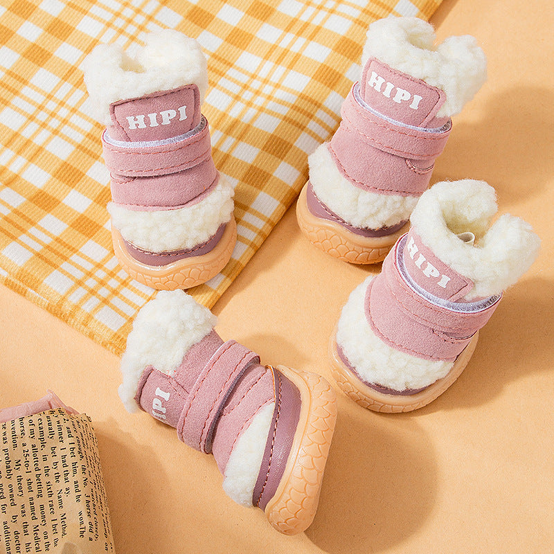 Four pink winter dog booties with white fleece lining and gum-colored soles displayed on yellow background