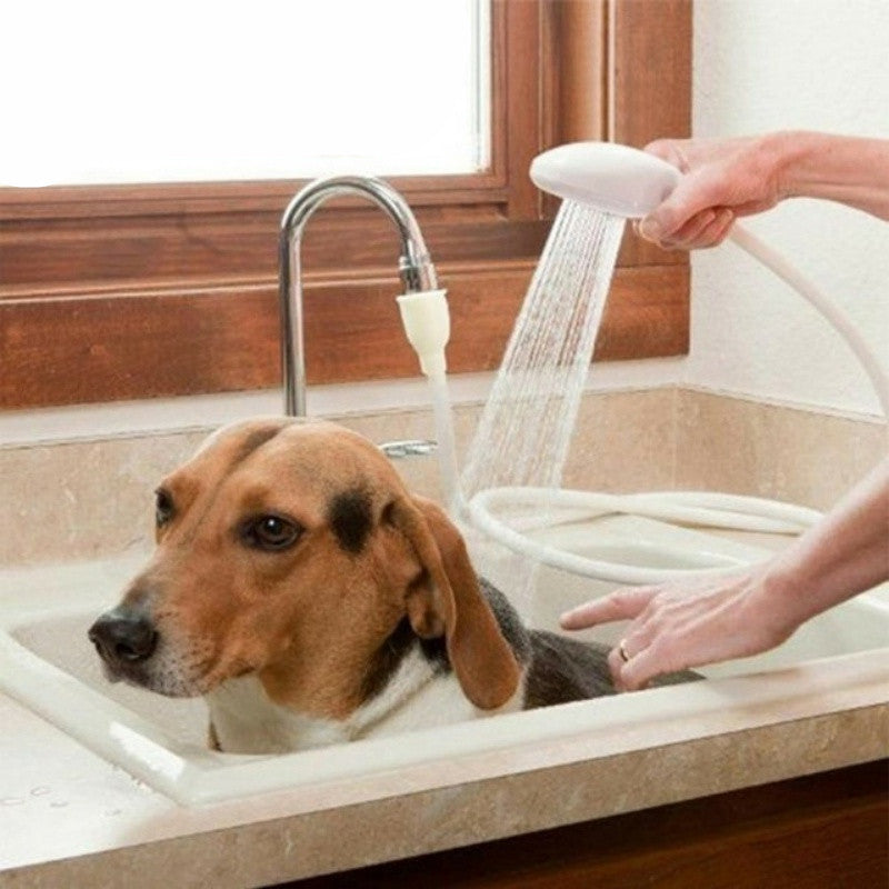 Hand holding white shower head spraying water on dog in a sink