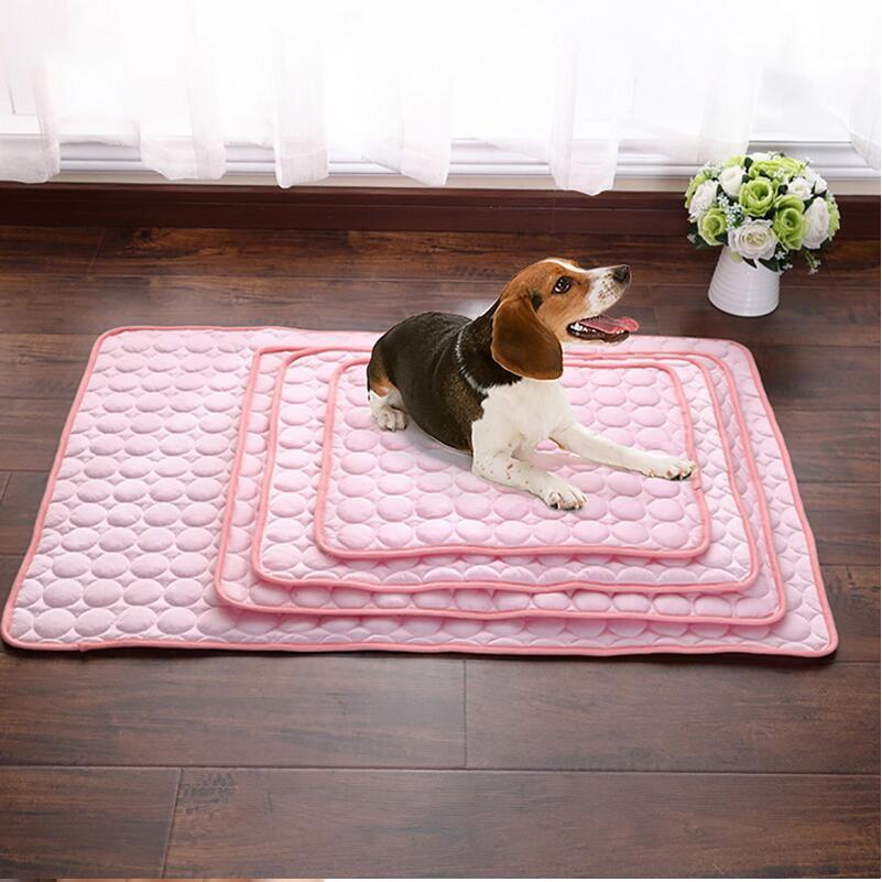 Beagle dog laying on layered soft pink pet cooling mats on wooden floor next to white flower vase