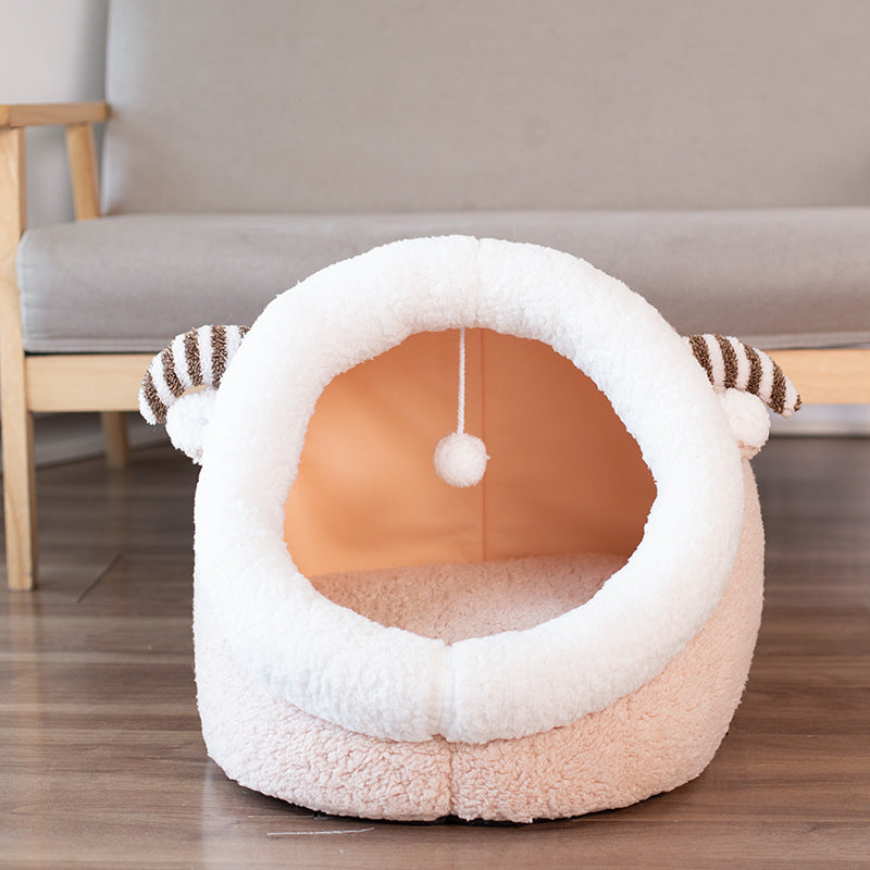 White plush pet house with brown striped horns and a hanging ball toy inside
