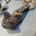 Charger l'image dans la visionneuse de la galerie, Close-up top-side view of a black crystal dog keychain with a sparkling wrist strap and gold connecting hardware
