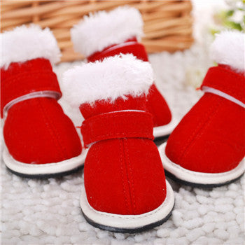 Front view of red winter pet boots with white faux fur lining on a soft surface
