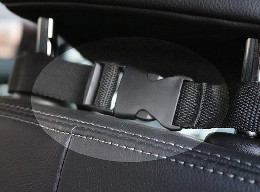 Close-up of black adjustable buckle strap securing car seat cover to headrest