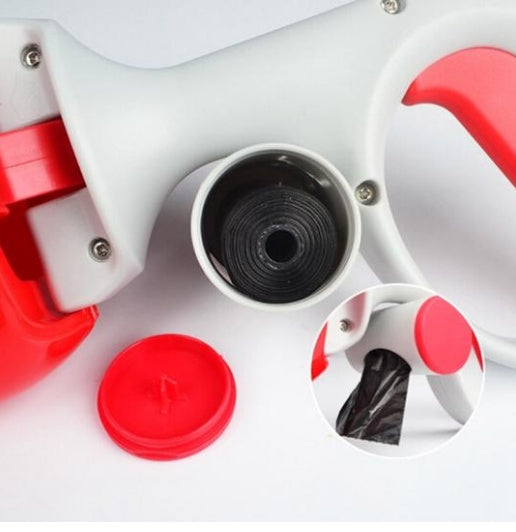 Close-up of red and gray portable dog waste scooper showing built-in compartment for black waste bag roll