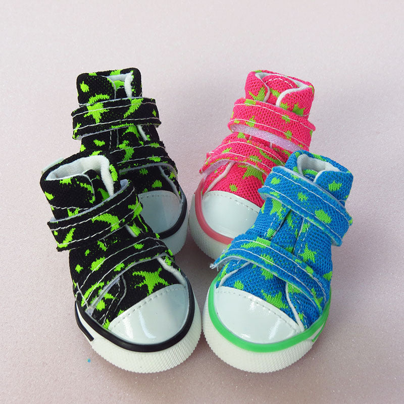 Three colorful high-top dog sneakers in black, pink, and blue with green star patterns and white rubber toe caps.