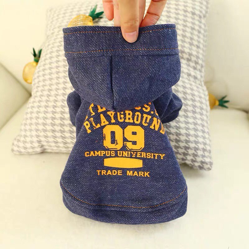 Hand holding the denim dog hoodie showing fabric texture and hood