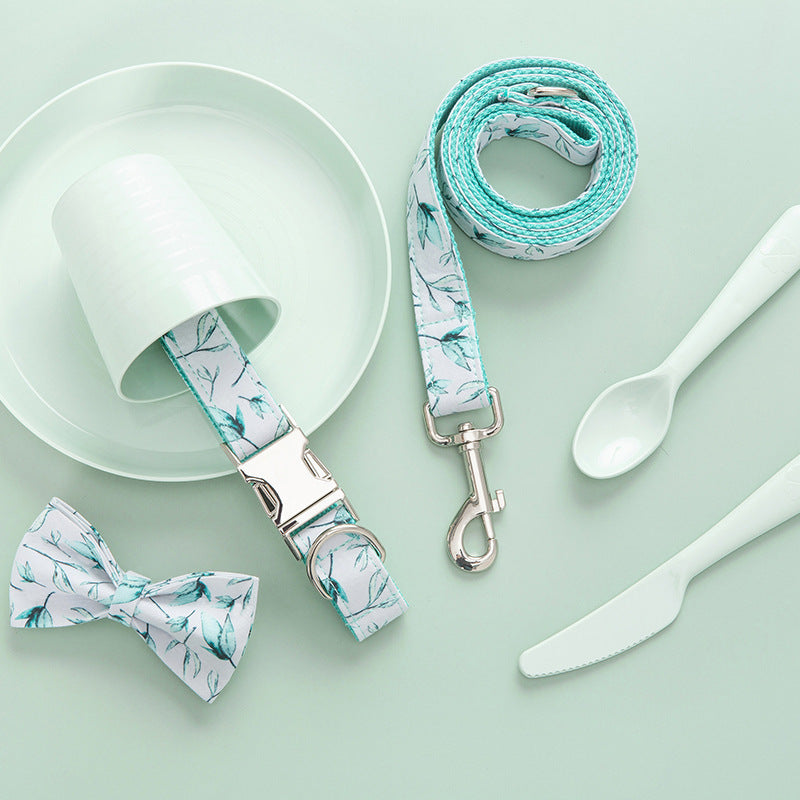 Leash coiled next to collar and bow tie on pastel green table setting